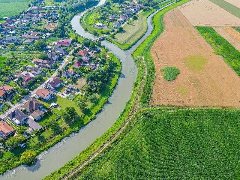 Řeka tekoucí podél zemědělských a lesních pozemků v Černé Vodě, vedle obce.