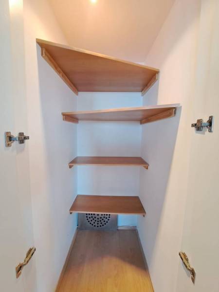 Šatník s vestavěnými policemi ve 4pokojovém bytě s podlahou s dřevěným dekorem.