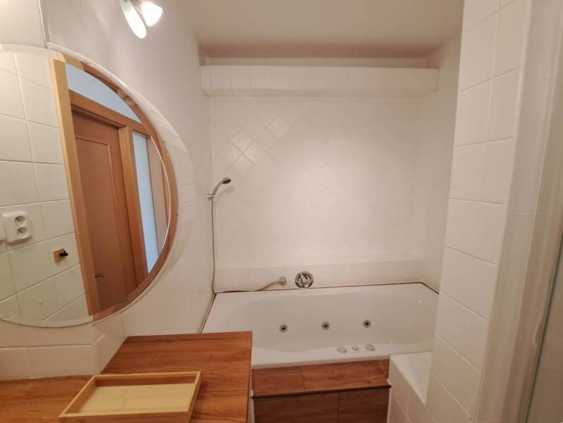 Koupelna se zrcadlem a vanou ve 4-pokojovém bytě; použití dřevěného dekoru.