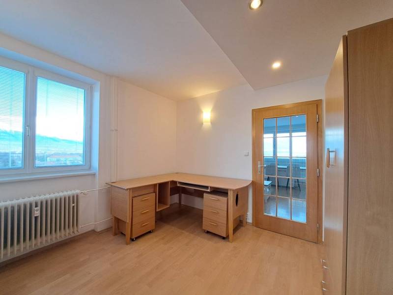 Pracovna ve 4-pokojovém bytě s podlahou s dřevěným dekorem a psacím stolem.