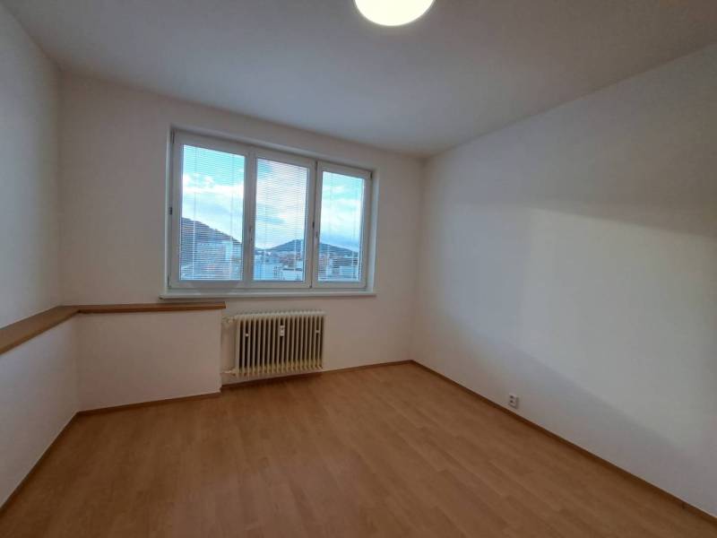 Pokoj ve čtyřpokojovém bytě s podlahou s dřevěným dekorem a velkým oknem.