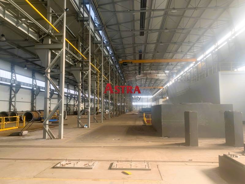 Výrobní prostory s kovovými konstrukcemi a jeřábem uvnitř haly.