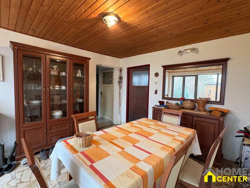 Jídelna v rodinném domě se stolem, židlemi a skříní, podlaha s dřevěným dekorem.