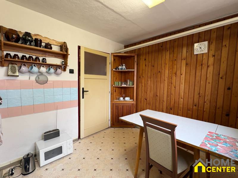 Kuchyňský kout v rodinném domě s dřevěným obkladem a retro vybavením.