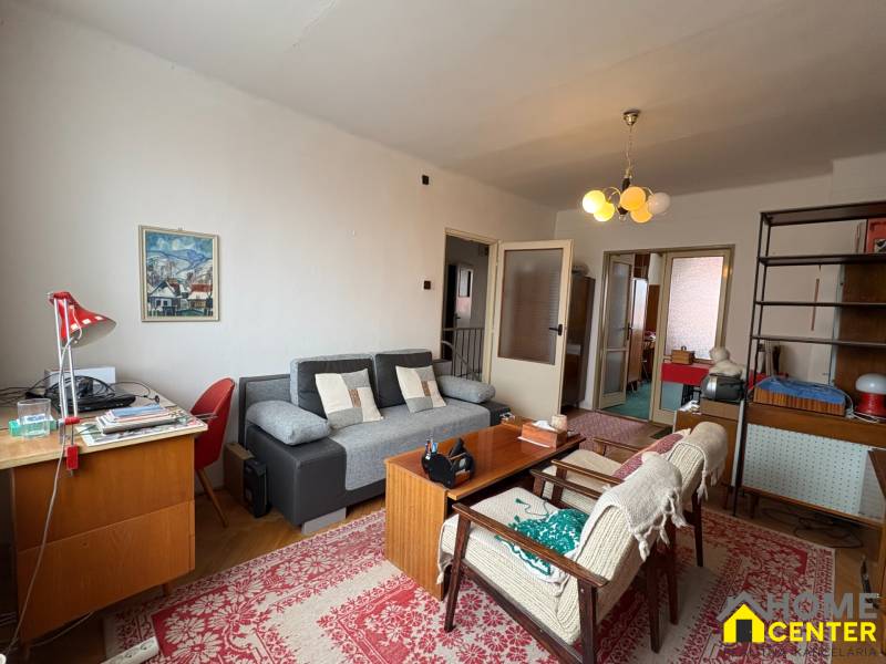 Obývací pokoj v rodinném domě s podlahou s dřevěným dekorem a retro nábytkem.