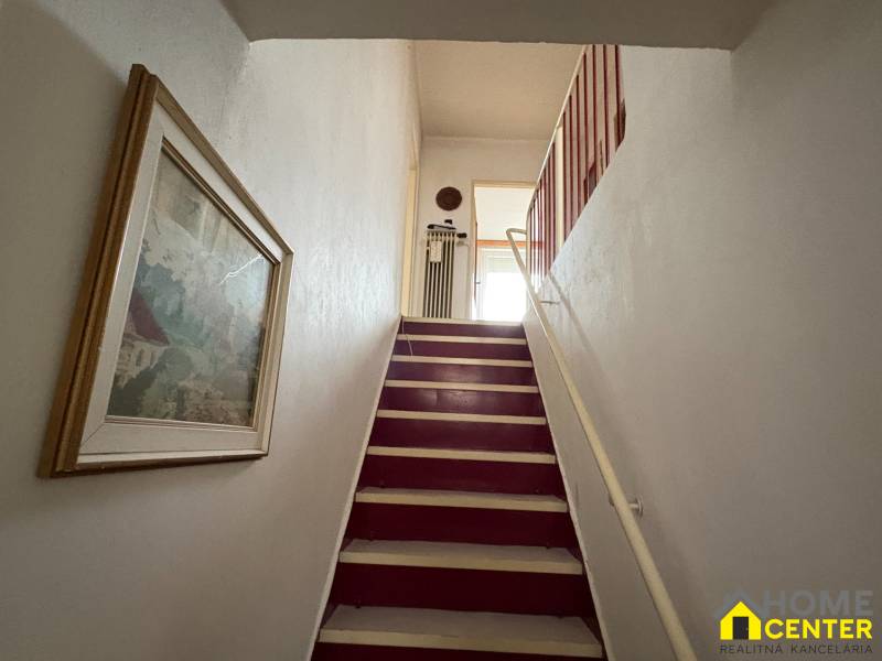 Schodiště v rodinném domě s obrazem na stěně.