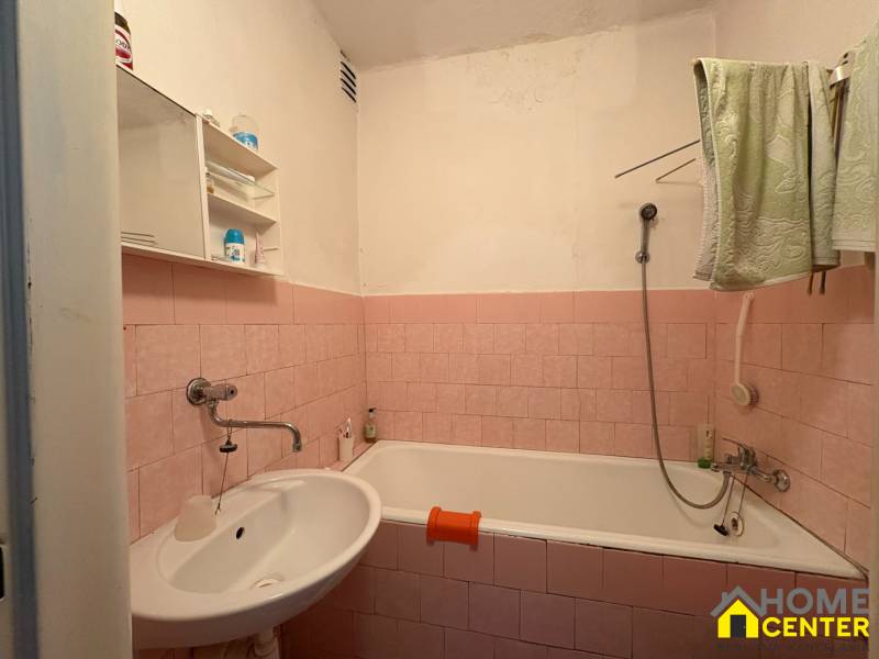 Koupelna v rodinném domě s růžovými kachličkami a bílým umyvadlem.