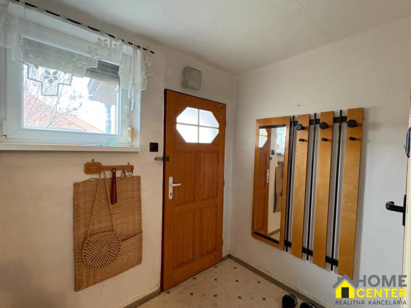 Vstupní hala rodinného domu s dřevěnými dveřmi a praktickým věšákovým systémem.