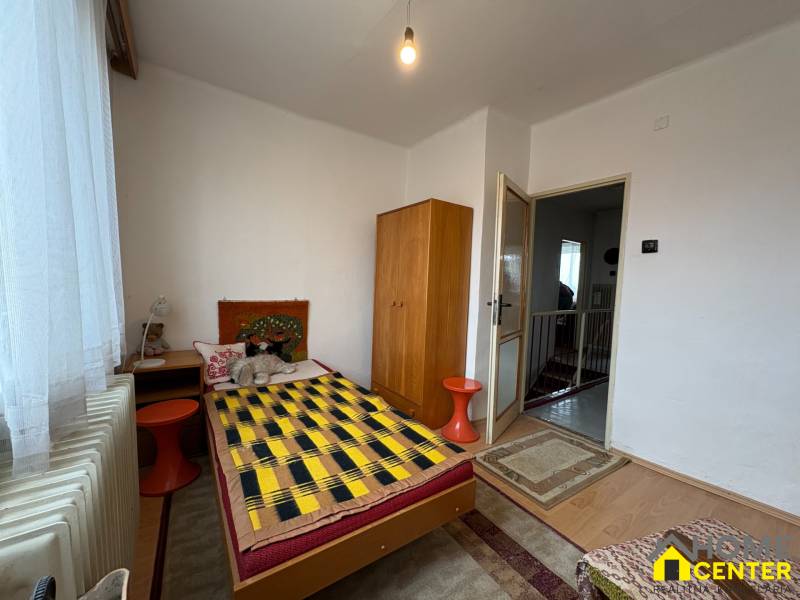 Pokoj v rodinném domě s jednolůžkem, skříňkou a podlahou s dřevěným dekorem.