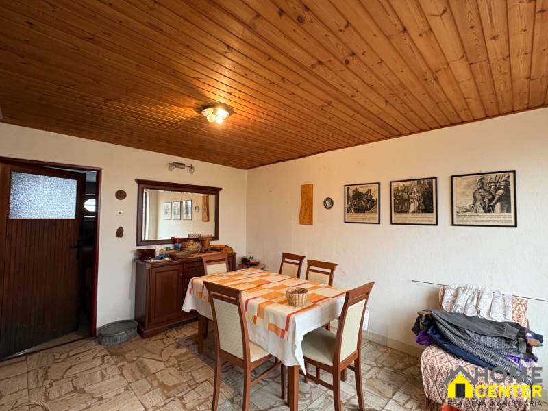 Jídelna rodinného domu s dřevěným stropem a dekorativními obrazy na stěně.