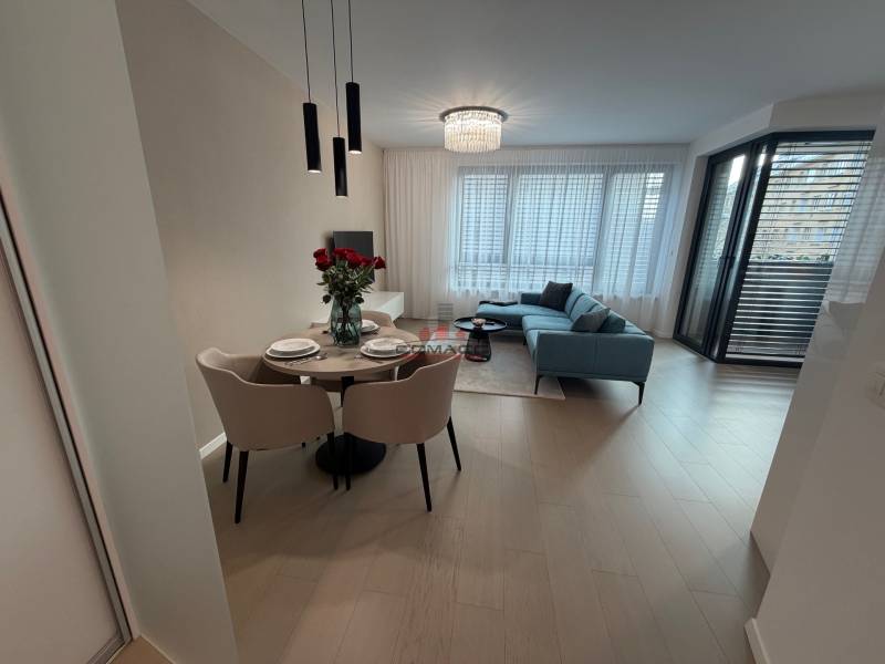 Interiér 2-pokojového bytu s podlahou s dřevěným dekorem, jídelním stolem a balkonem.