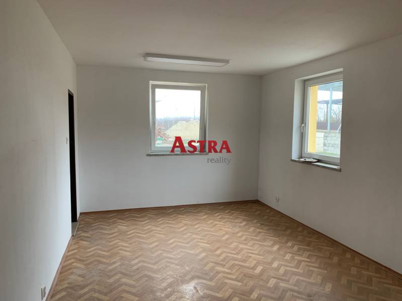 Prázdná místnost se dvěma okny a podlahou s dřevěným dekorem ve skladech a halách.