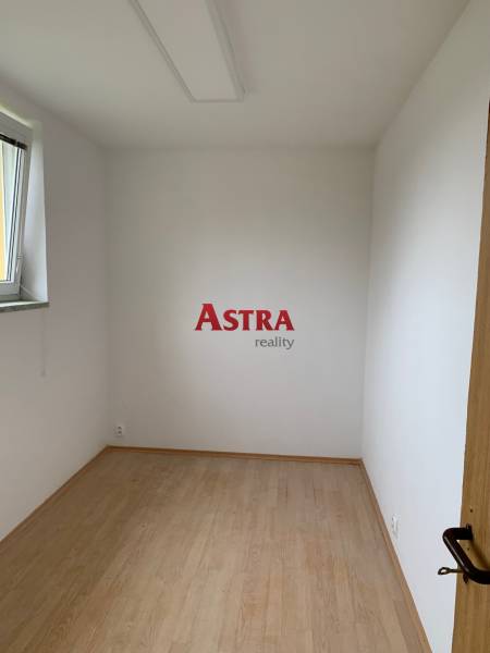 Malý pokoj s bílými stěnami a podlahou s dřevěným dekorem.