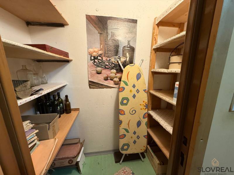 Úložný prostor s policemi a žehlicím prknem ve 3pokojovém bytě.