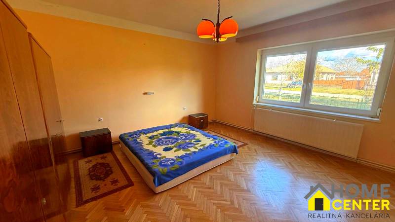 Ložnice v rodinném domě s podlahou s dřevěným dekorem a oranžovými stěnami.