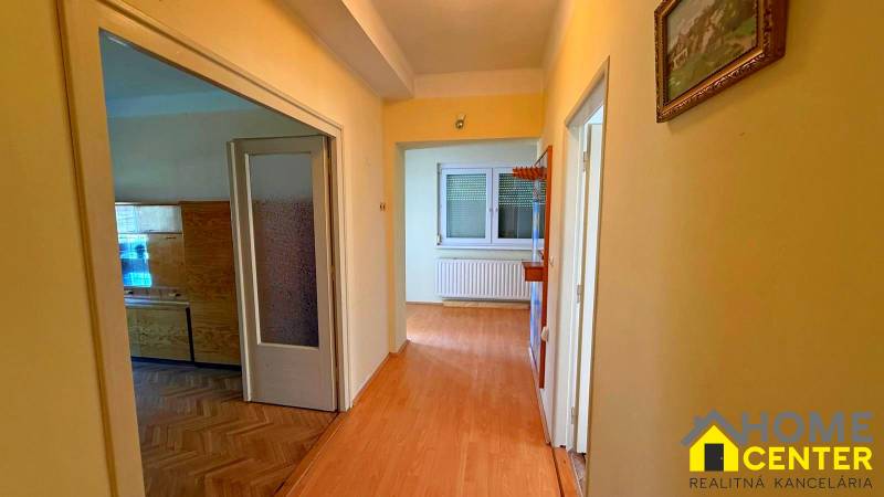 Chodba v rodinném domě s podlahou s dřevěným dekorem a obrazem na stěně.