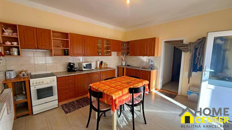 Kuchyně v rodinném domě s dřevěným dekorem a jídelním stolem.