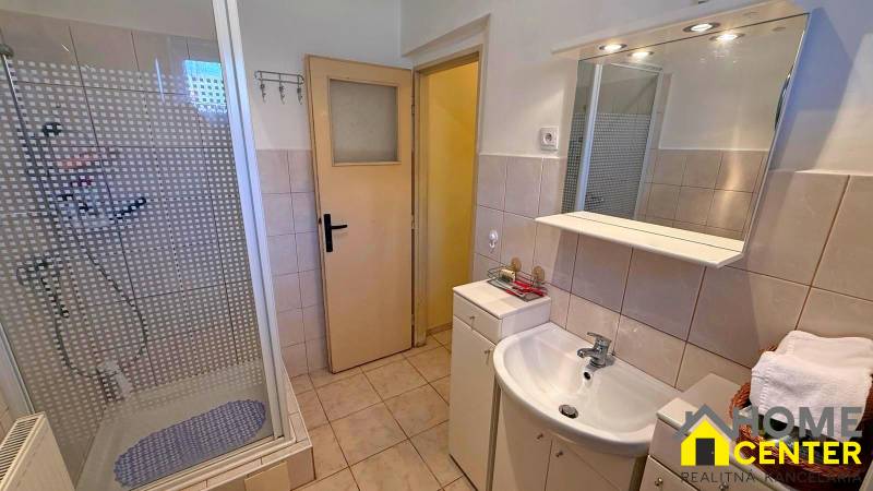 Koupelna v rodinném domě s umyvadlem, sprchovým koutem a obkladem.