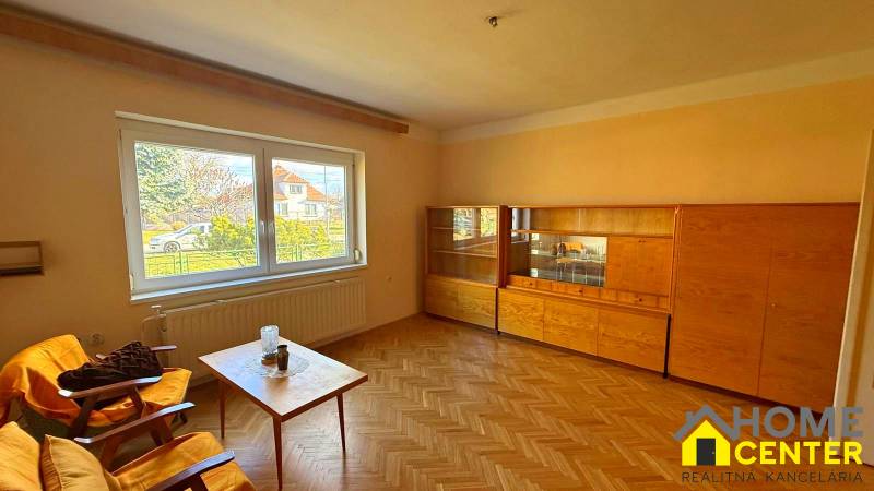 Obývací pokoj v rodinném domě s nábytkem a podlahou s dřevěným dekorem.