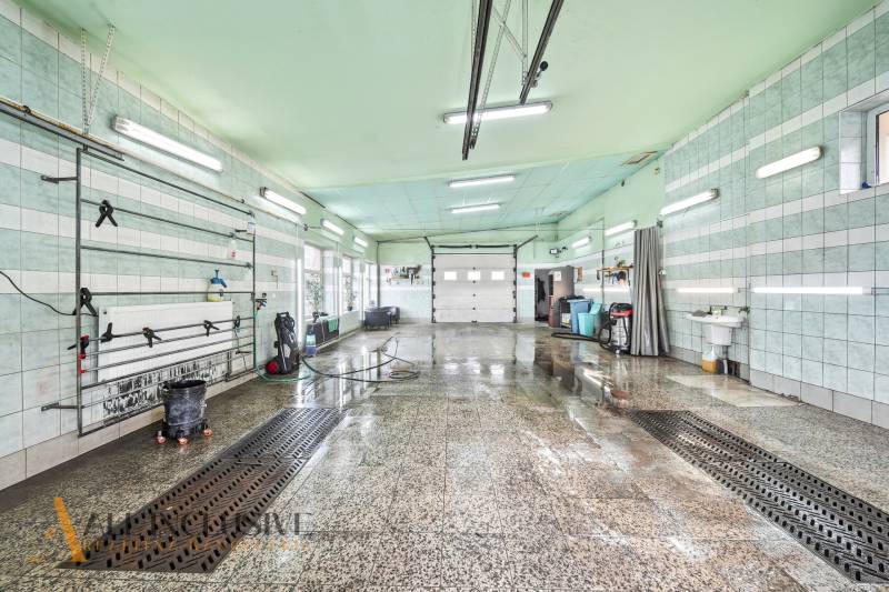 Interiérová mycí hala s mokrou podlahou a světelnými trubicemi na stropě.