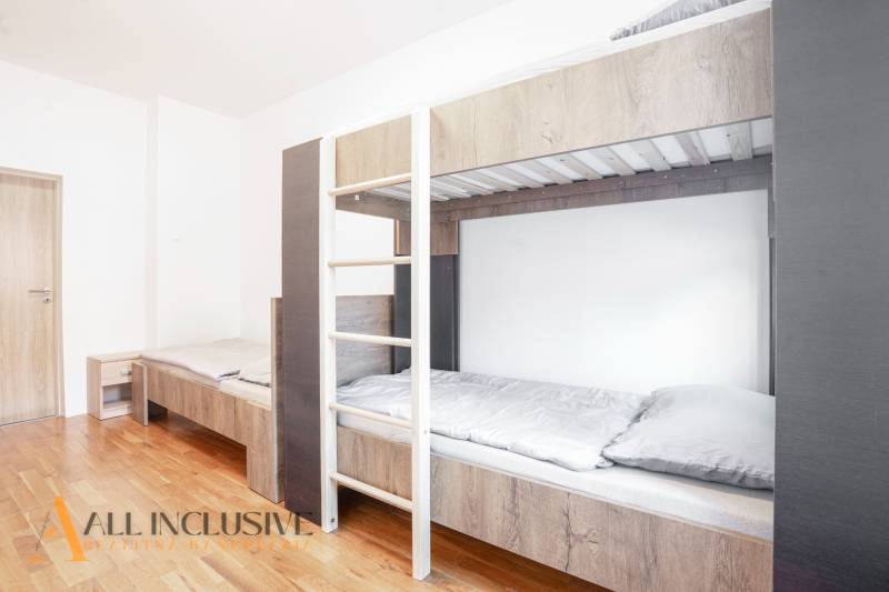 Interiér s patrovou postelí a podlahou s dřevěným dekorem v budově.