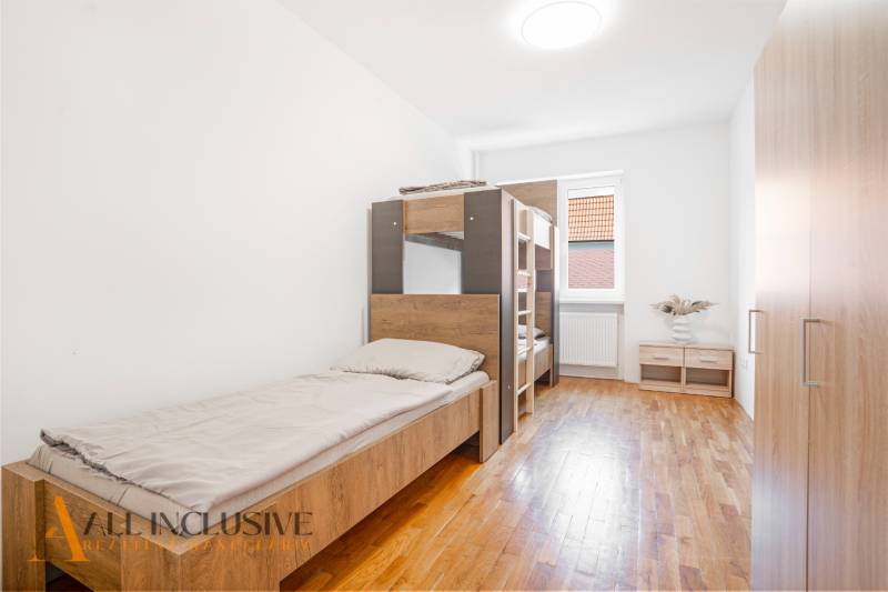 Interiér ložnice v budově s postelemi a podlahou s dřevěným dekorem.