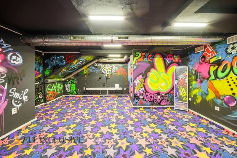Interiér budovy s graffiti na stěnách a barevným kobercem s hvězdami.