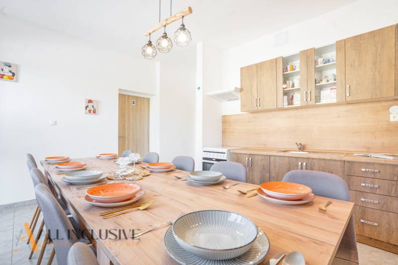 Kuchyně v budově, dřevěné skříňky, velký stůl s podlahou s dřevěným dekorem.