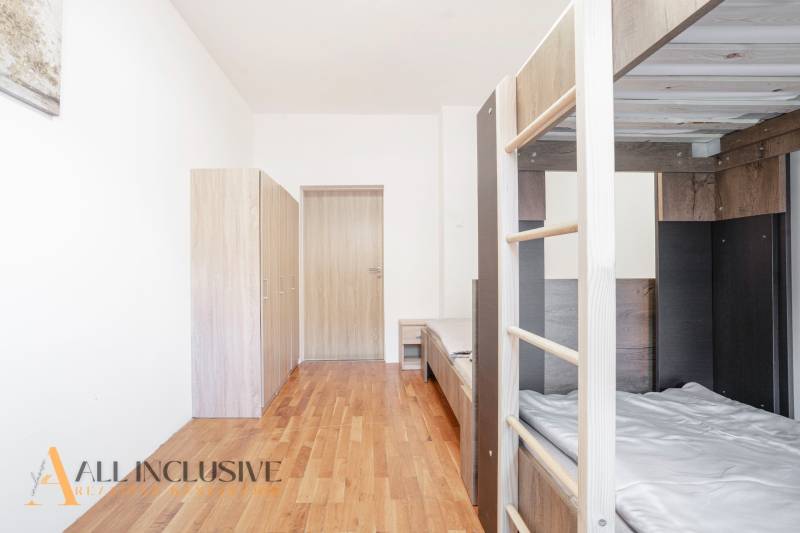 Interiér s patrovou postelí, skříně a podlaha s dřevěným dekorem.