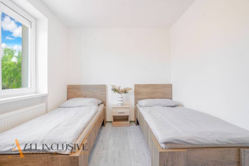 Pokoj s dvěma postelemi, nočním stolkem a podlahou s dřevěným dekorem.