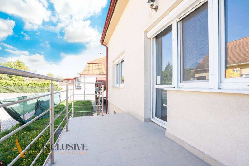 Budova v Dunajské Stredě s terasou a zábradlím, obloha s oblaky.