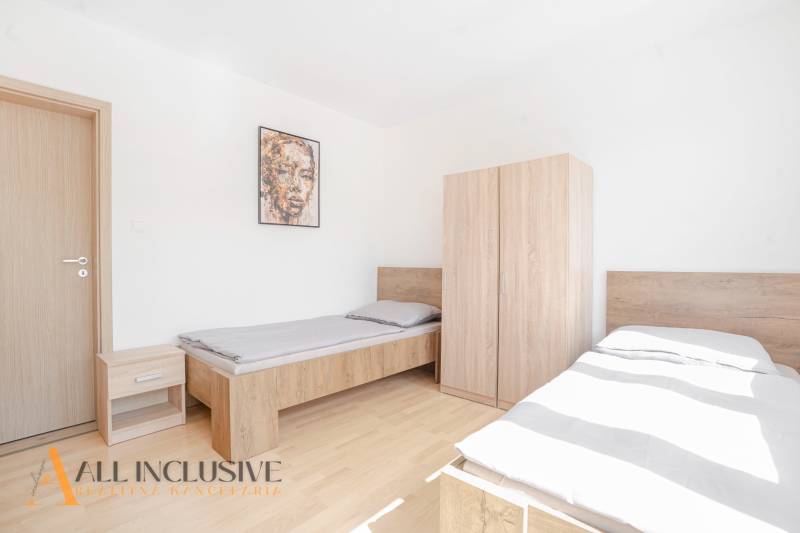 Ložnice s dvěma postelemi a nábytkem, podlaha s dřevěným dekorem, obraz na stěně.