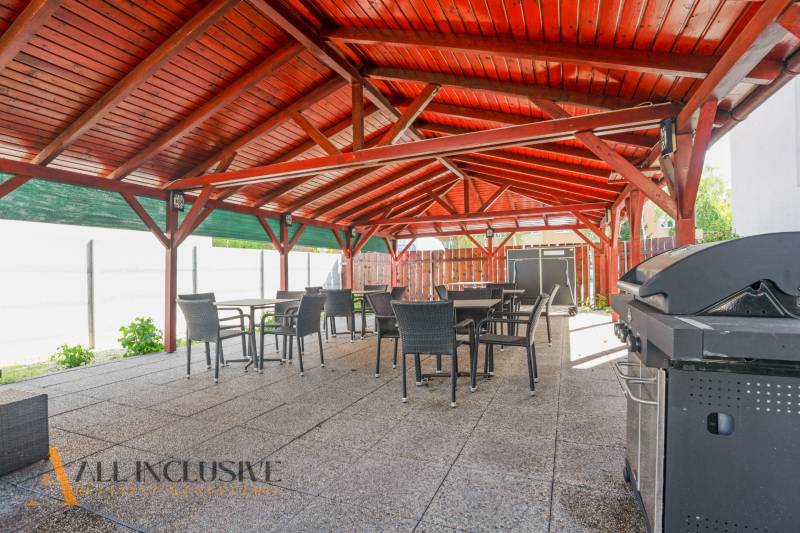 Exteriérová terasa budovy v Dunajskej Strede s dřevěnou střechou a grilem.