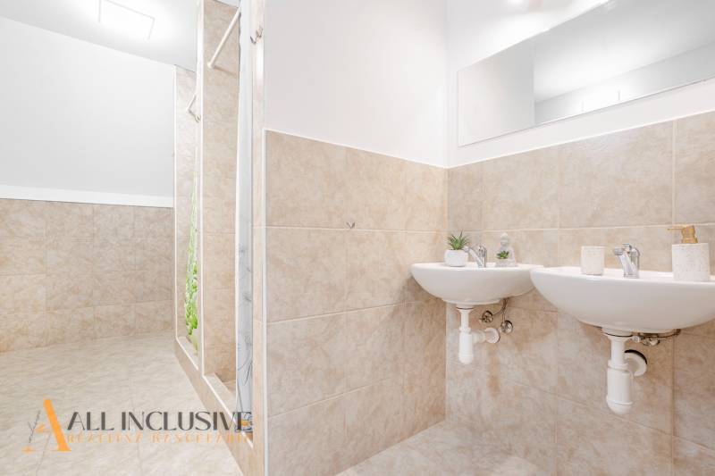 Koupelna se dvěma umyvadly a sprchou, dekorativní kachličky a zrcadlo v budově.