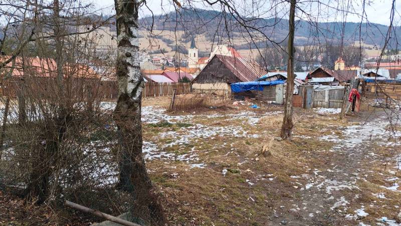 Zasněžené zahrady v Nálepkově s chatkami a výhledem na kopce a kostel.