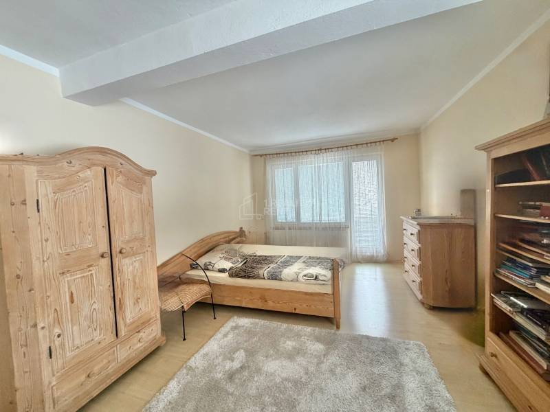 Ložnice v rodinném domě s dřevěným nábytkem a podlahou s dřevěným dekorem.