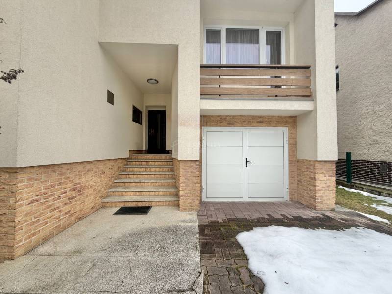 Rodinný dům na Čadečce v Čadci se schody a garáží, zbytky sněhu na příjezdové cestě.