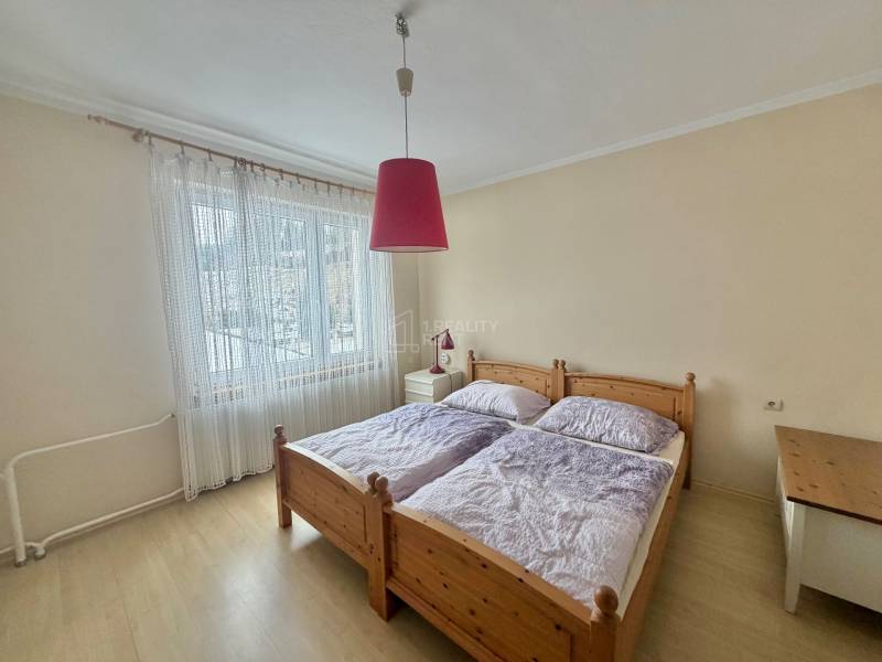 Ložnice s manželskou postelí a lustrem v rodinném domě s podlahou s dřevěným dekorem.