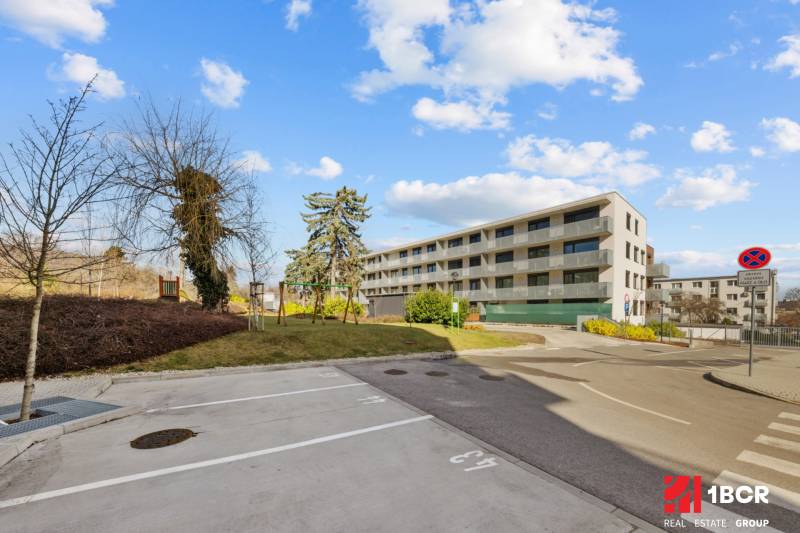 Bytový dům na Skalické cestě v Bratislavě - Novém Městě. V popředí jsou parkovací místa.