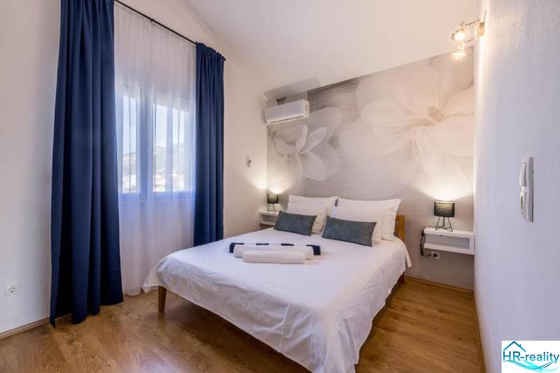 Ložnice ve vile s velkými květinami na stěně a podlahou s dřevěným dekorem.