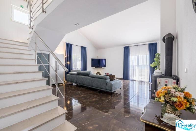 Obývací pokoj vily s lesklou podlahou a modrými závěsy.