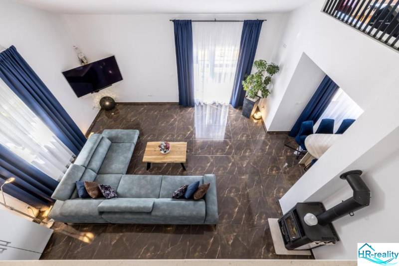 Vila s výhledem na obývací pokoj s modrou sedačkou a mramorovou podlahou.