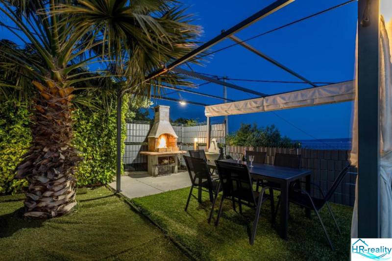 Palmová zahrada vily v Kaštela s pergolou, krbem a stolem.