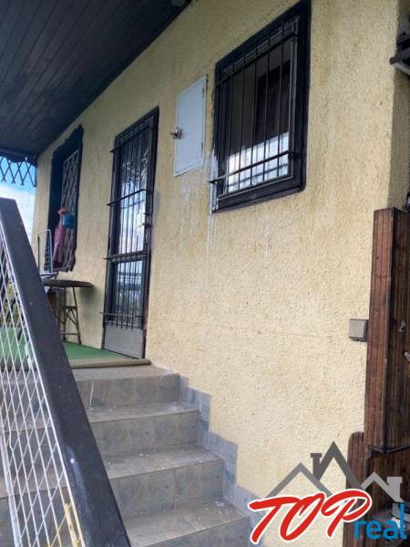 Vstupní schody a okenní mříže chaty ve Vyšném Opátském, Košice, se žlutou fasádou.