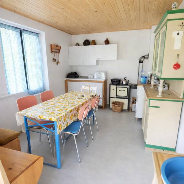 Kuchyně na chatě s barevnými židlemi a květinovým ubrusem na stole.