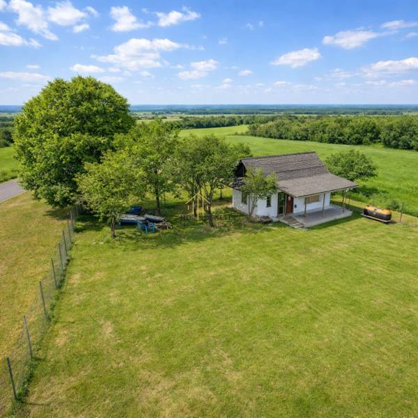 Chata v Obeckově obklopená velkou travnatou zahradou a stromy.