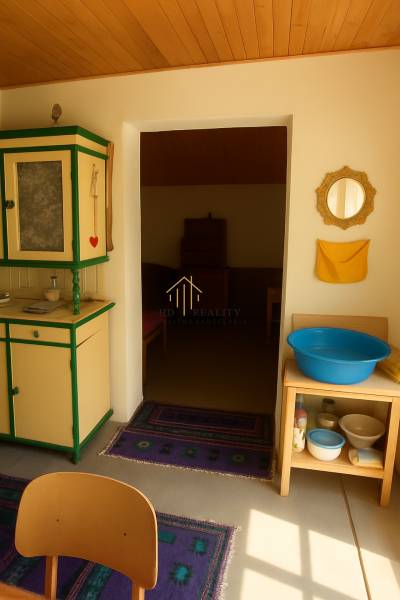 Interiér chaty s dřevěným dekorem stropu, vintage nábytkem a modrou lavórou.