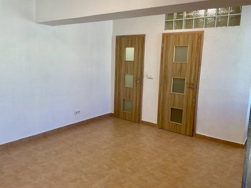 Interiér 1-pokojového bytu s keramickou podlahou a dvěma dveřmi s dřevěným dekorem.