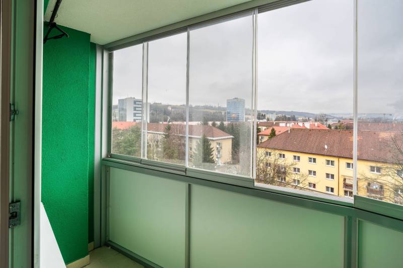 Zasklený balkon s výhledem na budovy na Třída SNP v Banské Bystrici.