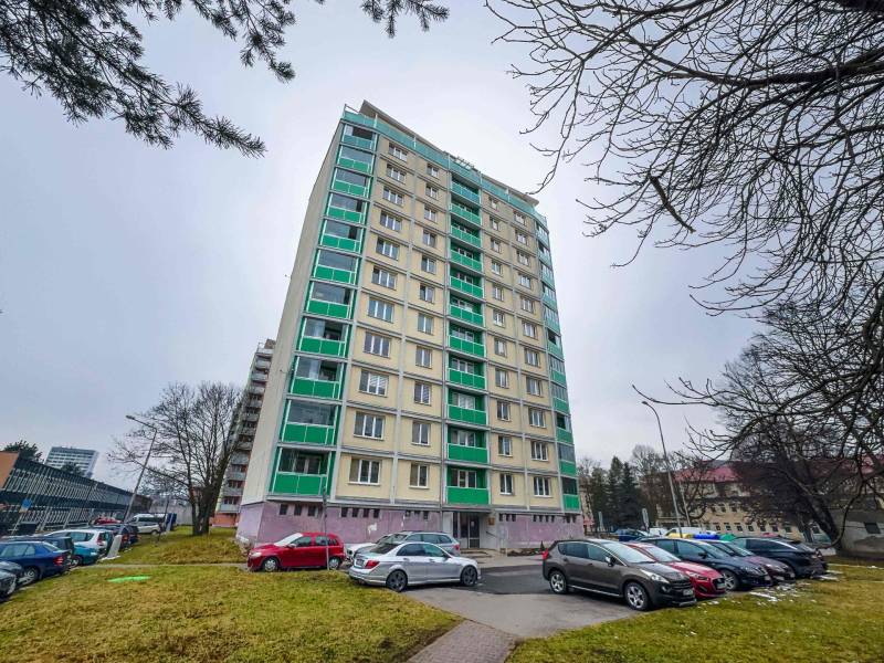 Výškový bytový dům na Třídě SNP v Banské Bystrici s parkovištěm v popředí.